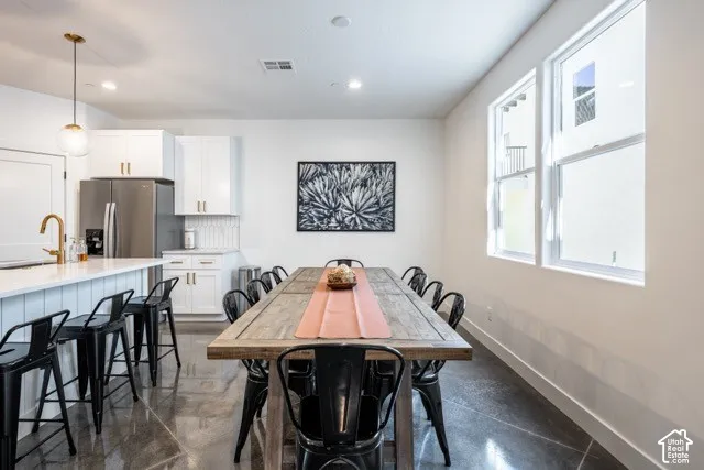 Gleaming polished concrete flooring, white shaker cabinetry, stainless steel appliances, and a kitchen island with shiplap detailing