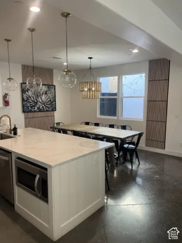 Kitchen island with white paneled cabinetry, quartz countertop, and a built-in microwave