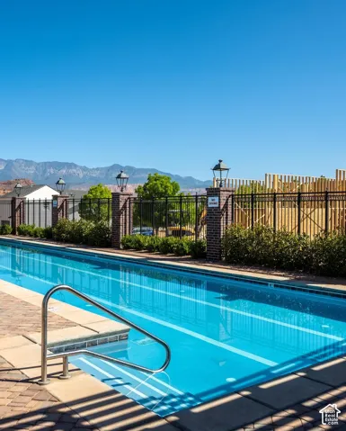 Resort-style swimming pool featuring crystal-blue water, stainless steel handrails, and surrounding paved decking