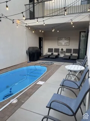 Outdoor patio featuring a built-in swimming pool, brick paver coping, and concrete decking