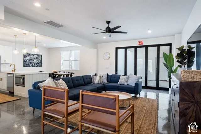 Open-concept living space featuring high ceilings, polished concrete flooring, and a modern ceiling fan