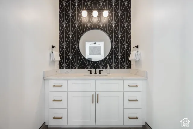 White vanity with gold-finish hardware, a white countertop, and a black faucet