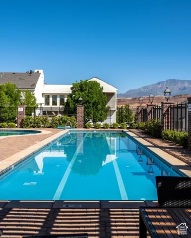 Rectangular swimming pool with lane markers, brick paver decking, and an adjacent spa