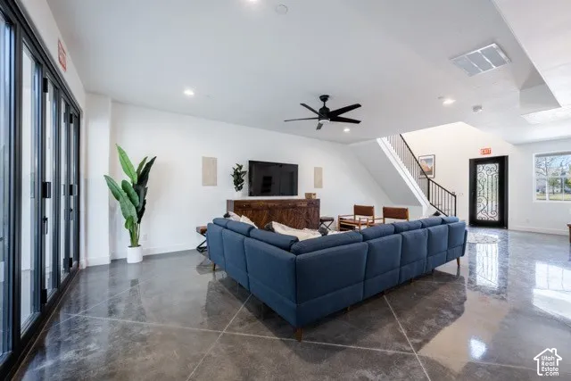 Polished concrete flooring, recessed lighting, ceiling fan, and large folding glass doors
