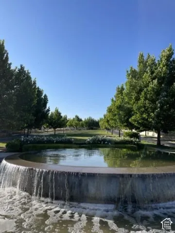 Circular water feature with cascading water, surrounded by manicured landscaping, mature trees, and an expansive lawn