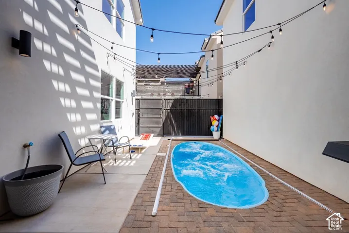 Private courtyard featuring a plunge pool, brick paver hardscaping, and string lighting
