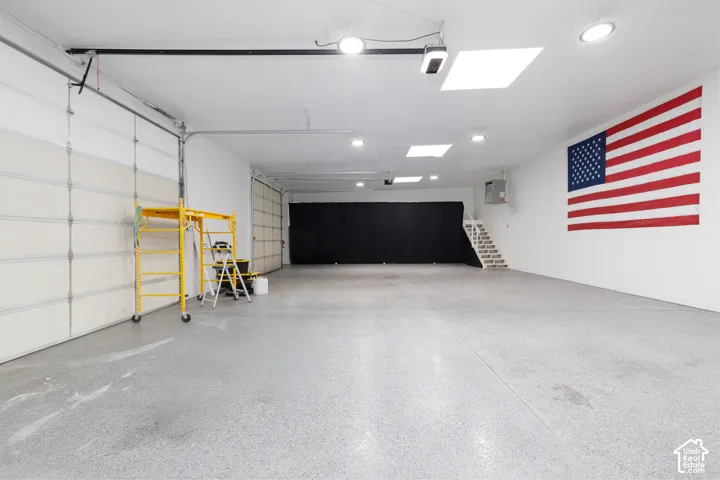 Spacious garage with two overhead doors, a finished concrete floor, recessed lighting, and dual skylights