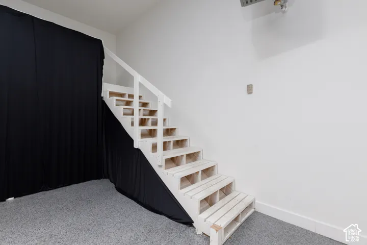 White painted staircase with open risers, white handrail, and gray speckled flooring