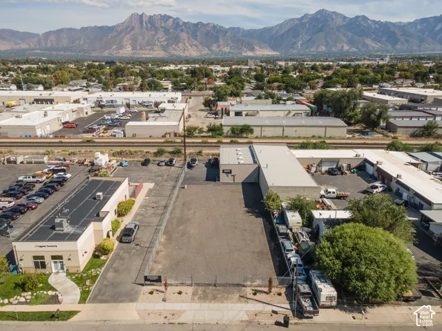 Expansive paved lot with mountain backdrop, surrounded by commercial buildings
