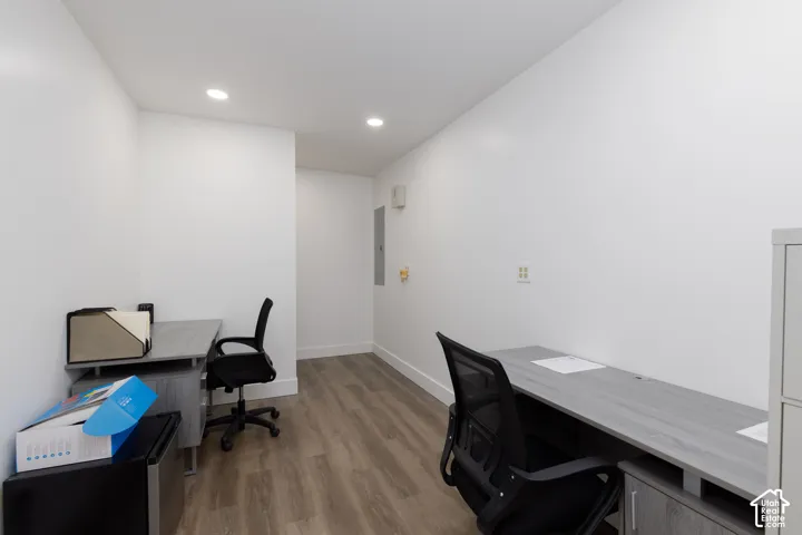 Recessed lighting, wood-finish flooring, white walls, and a built-in electrical panel