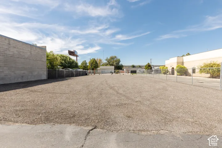 Expansive gravel lot featuring perimeter chain-link fencing and a concrete block wall