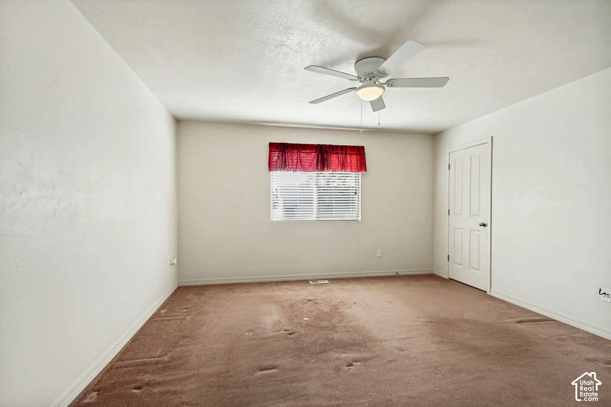 White-painted walls, a ceiling fan with integrated lighting, a window with horizontal blinds, and a white interior door