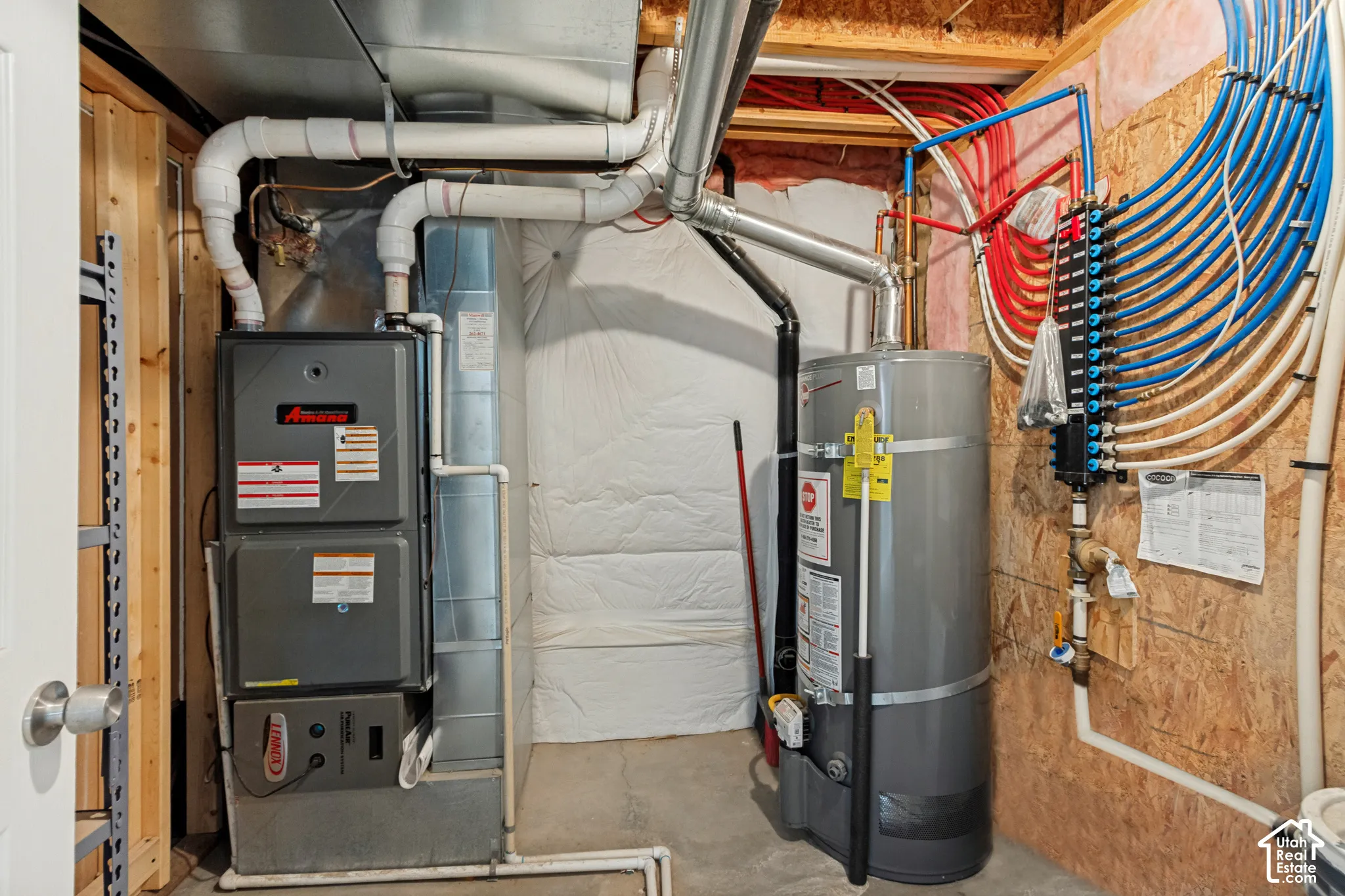 Dedicated utility area featuring a water heater, furnace, and PEX plumbing manifold