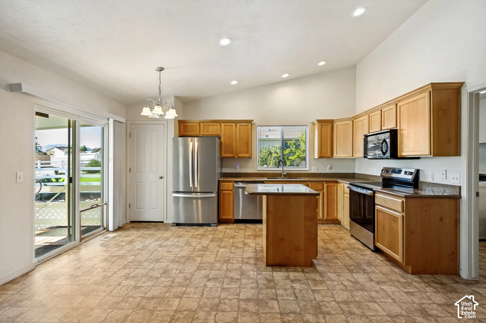 Kitchen with wood cabinetry, stainless steel appliances, a center island, and granite-style countertops