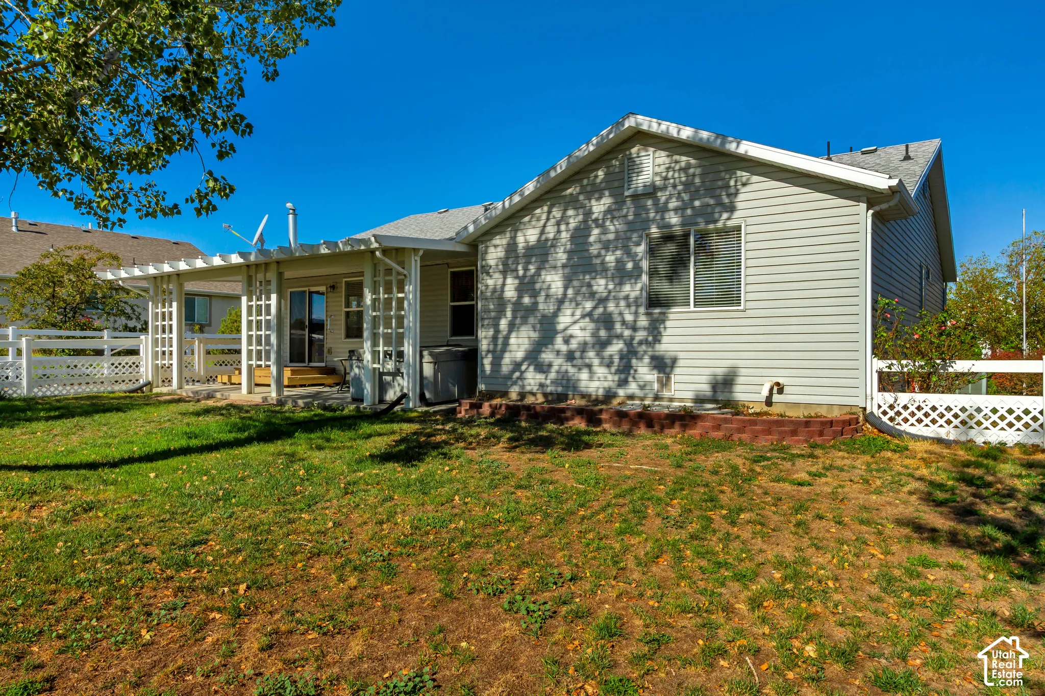 Rear exterior with siding, white lattice fencing, and a covered patio structure