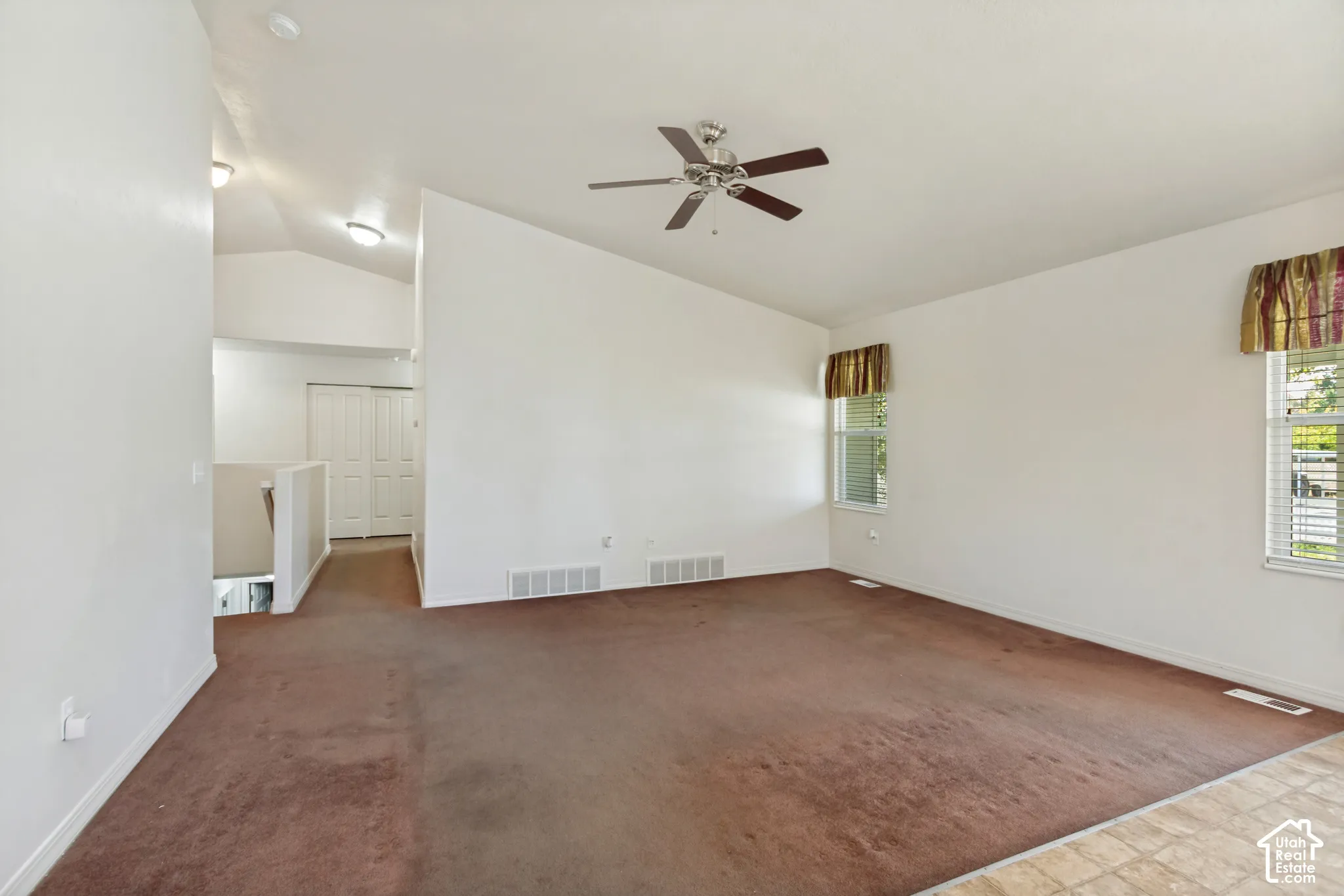 Vaulted ceiling, ceiling fan, two windows, two-panel closet doors, and mixed flooring
