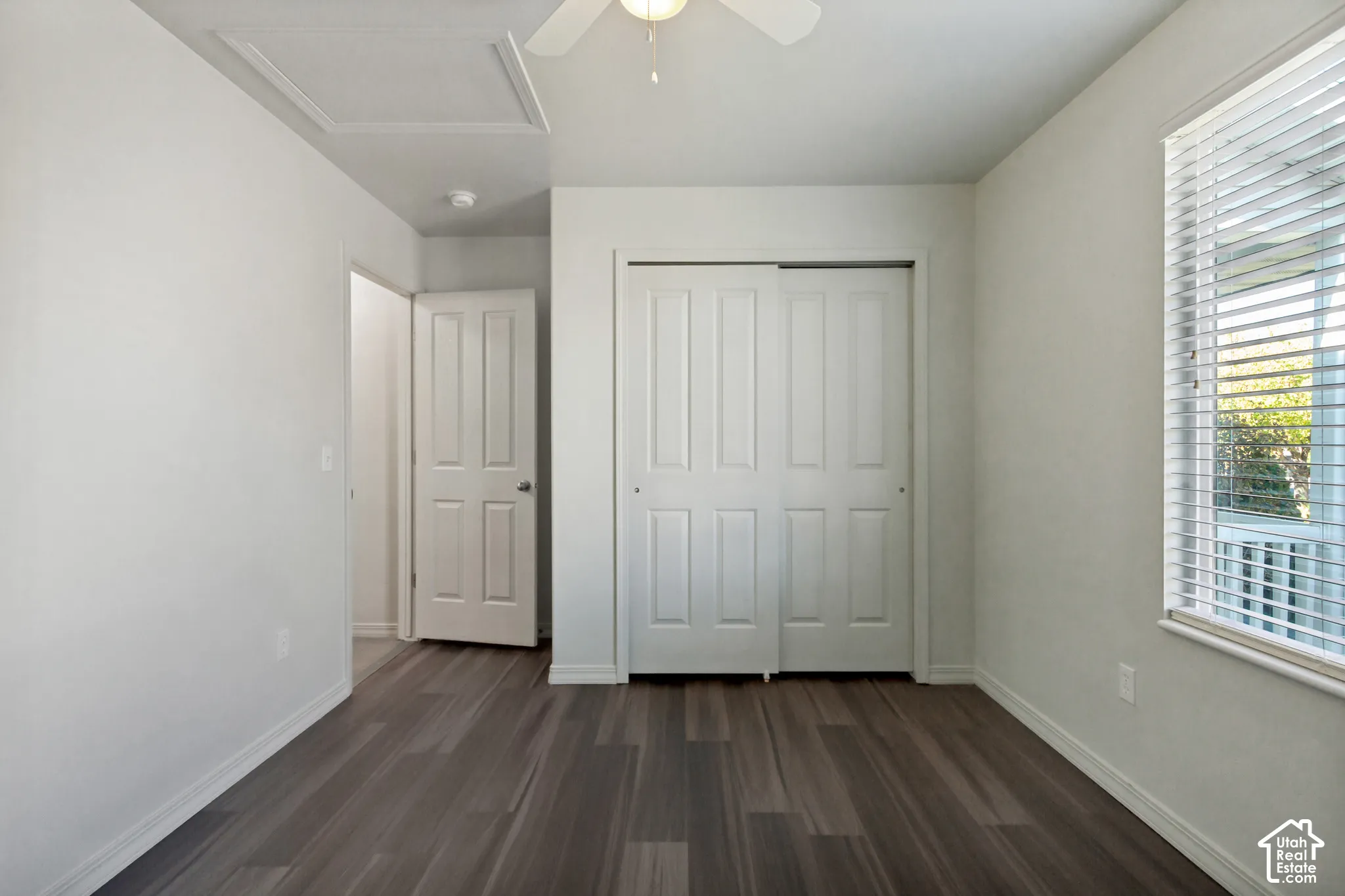 Wood-finish flooring, white walls, and a window with blinds