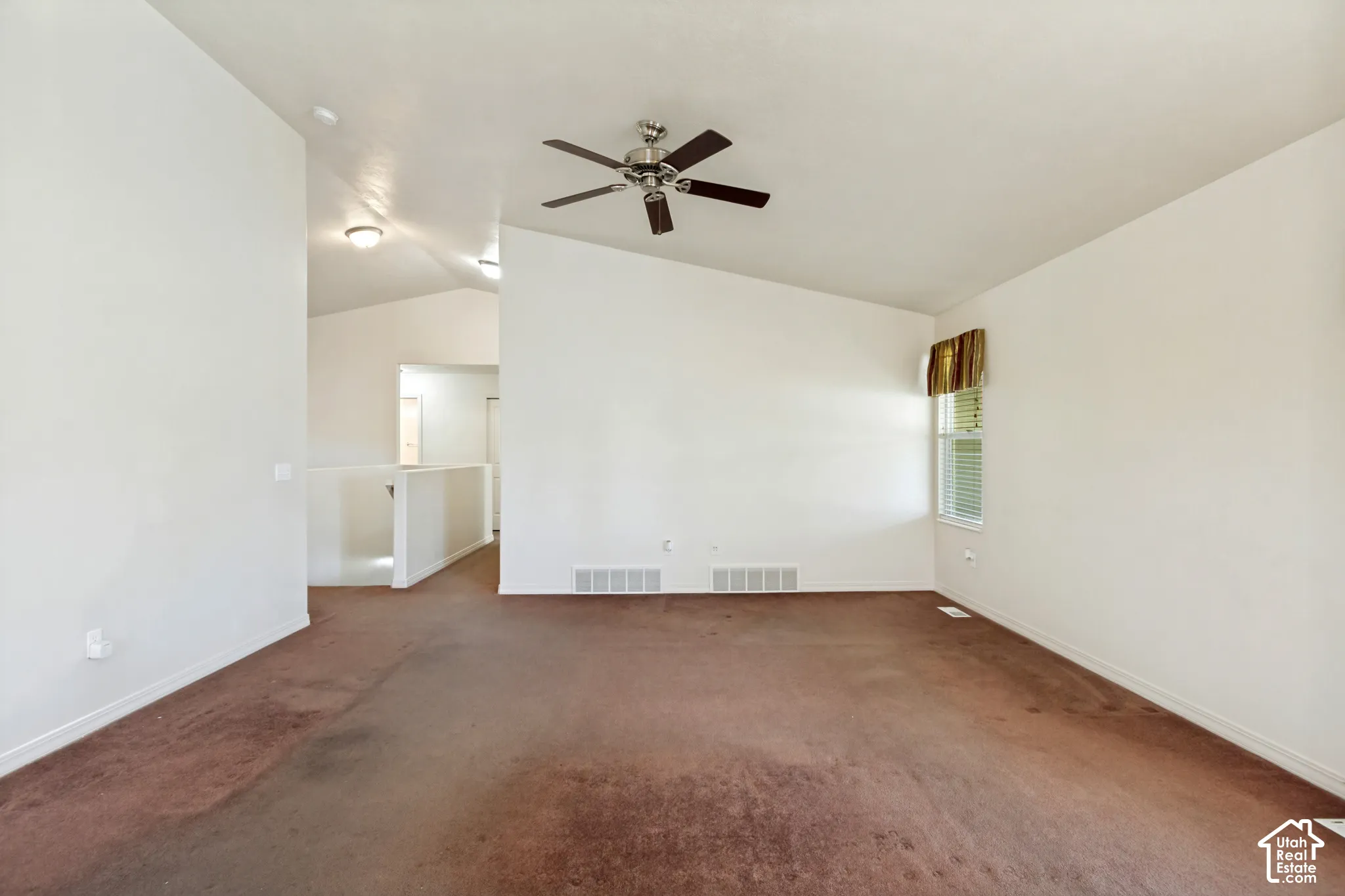 Vaulted ceiling with a ceiling fan, window with blinds, and white interior walls