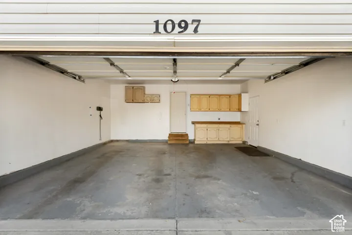 Interior garage featuring built-in cabinetry, overhead lighting, and an additional access door