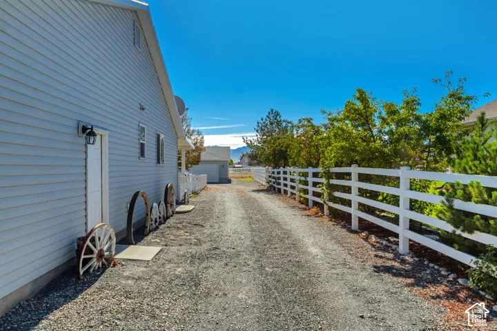 Gravel driveway with white fencing and mature landscaping