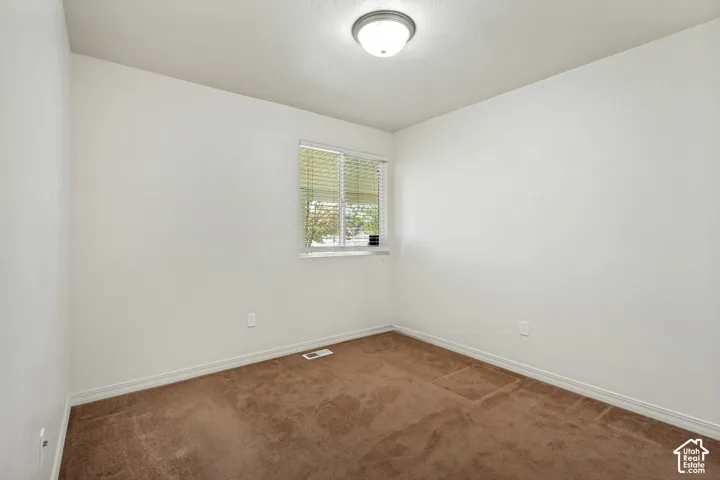 Neutral wall paint, window with blinds, flush-mount ceiling light fixture, and brown carpet flooring