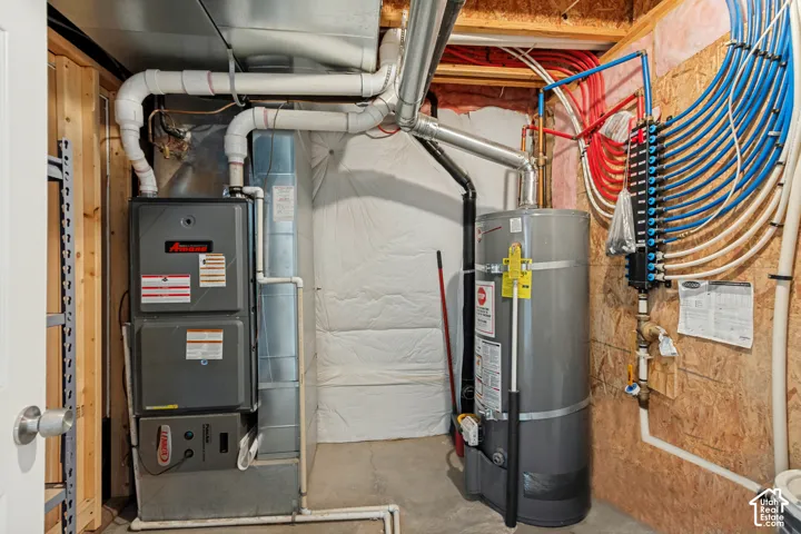 Dedicated utility area featuring a water heater, furnace, and PEX plumbing manifold