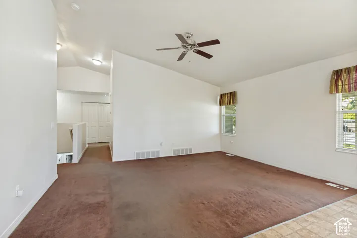 Vaulted ceiling, ceiling fan, two windows, two-panel closet doors, and mixed flooring