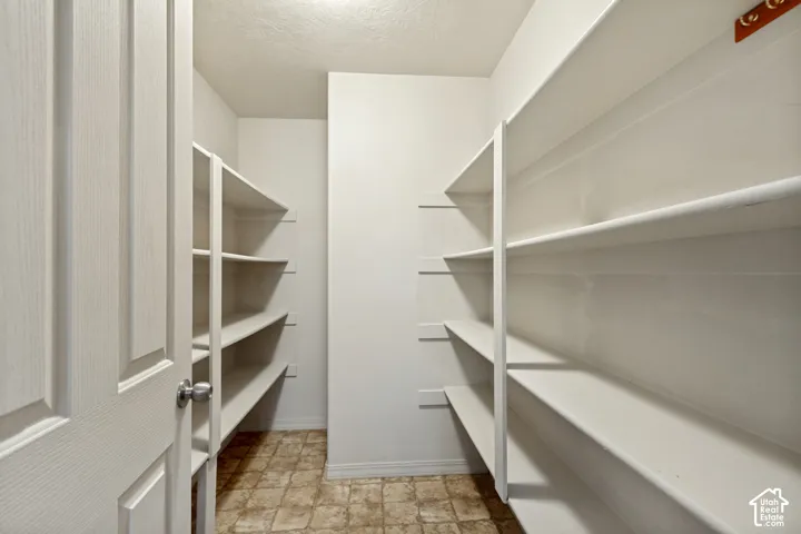 Walk-in pantry featuring multiple built-in shelves and patterned tile flooring