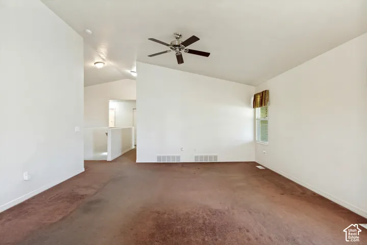 Vaulted ceiling with a ceiling fan, window with blinds, and white interior walls