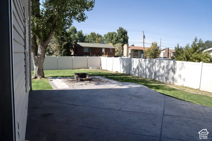 Stamped concrete patio with a fire pit, surrounded by a manicured lawn and a privacy fence