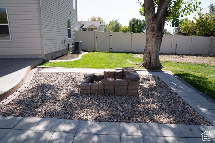 Backyard space featuring a stone-block fire pit, gravel landscaping, and concrete paver patio