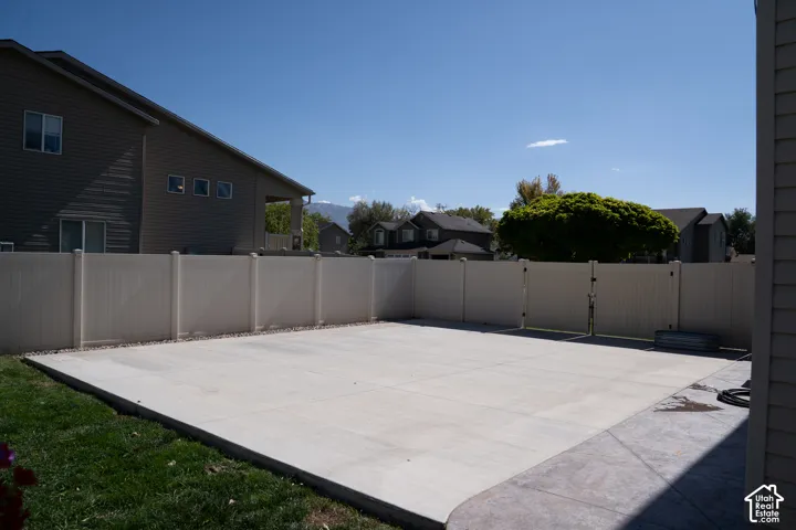Expansive concrete patio with a full privacy fence and a gated access point