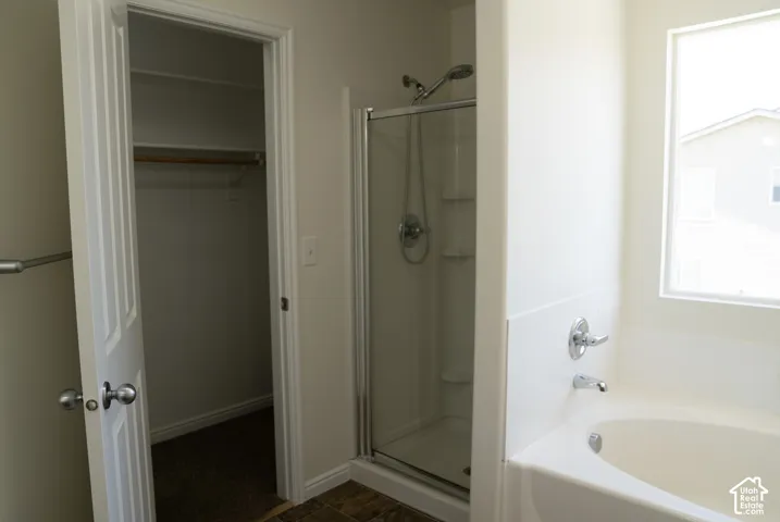Built-in closet with hanging rod, glass-enclosed shower, built-in bathtub, and window