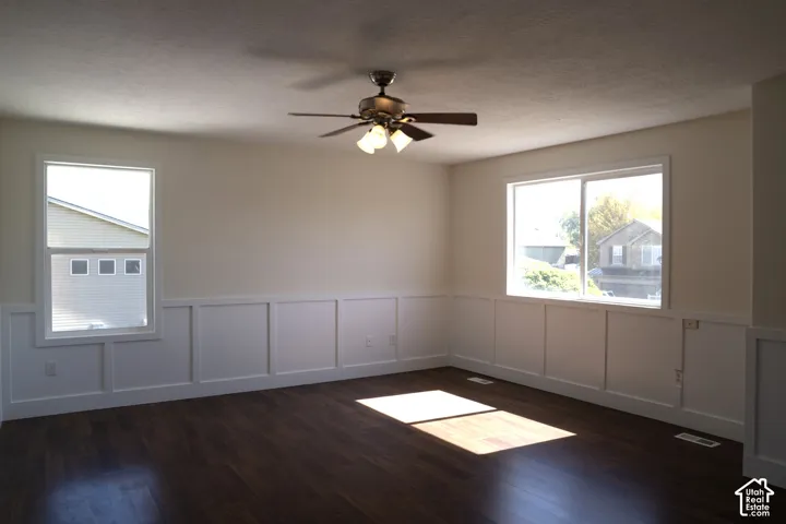 Wood-finish flooring, wainscoting, and a ceiling fan with integrated lighting