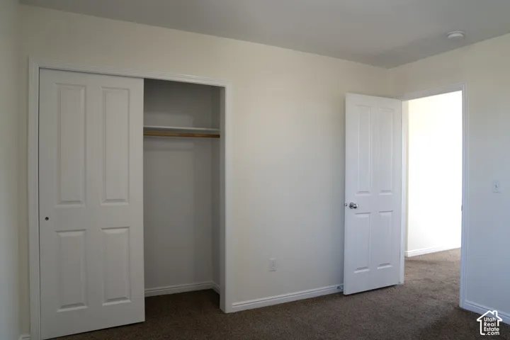 Room featuring neutral wall paint, brown carpeting, a paneled interior door, and a closet with sliding paneled doors and a built-in shelf and rod