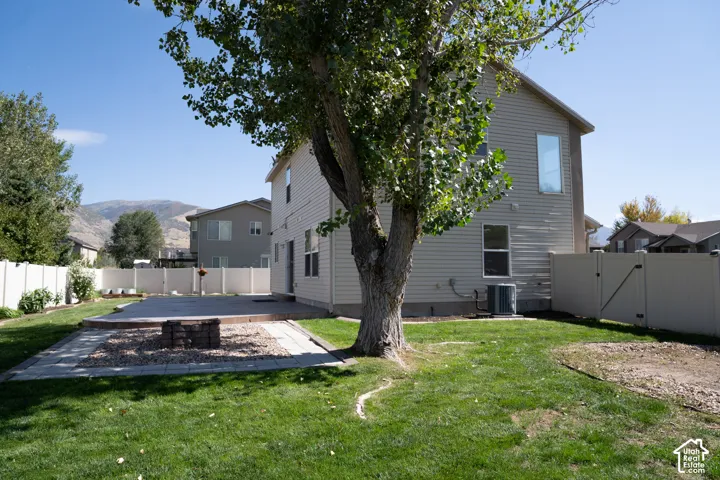 Expansive backyard featuring a manicured lawn, a large paver patio, a built-in fire pit with gravel surround, and a privacy fence