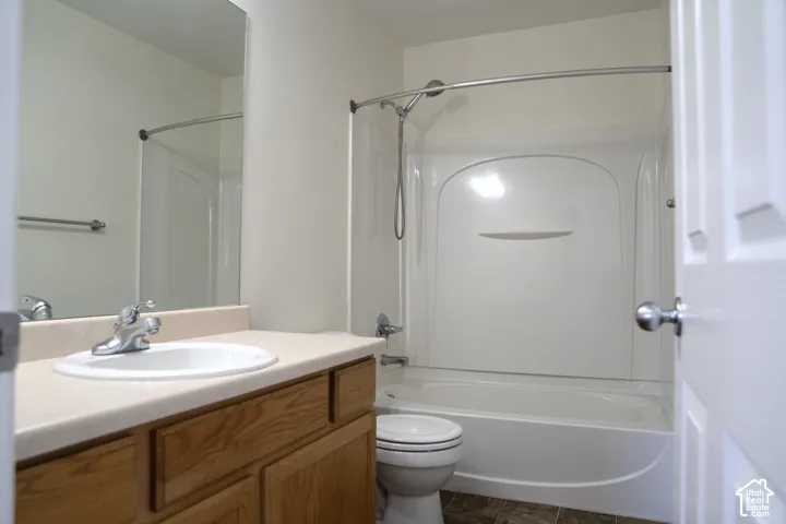 Bathroom featuring a wood-finish vanity with a laminate countertop, an integrated sink, a full-width mirror, and a shower-over-tub combination with a curved shower rod