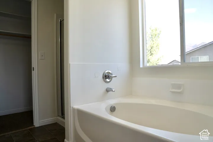 Built-in soaking tub with chrome fixtures, a window above, and ceramic tile flooring