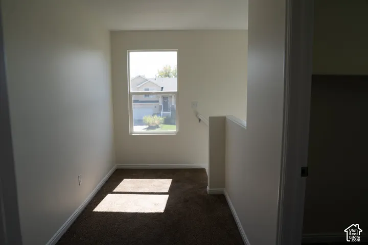 Carpeted area with a single-pane window, neutral-toned walls, and white trim