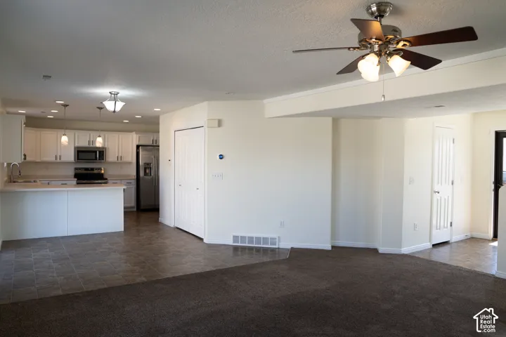 Open-concept living space with a ceiling fan, recessed lighting, and mixed flooring