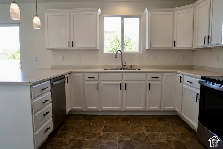 Spacious kitchen featuring white shaker-style cabinetry with brushed nickel hardware, stainless steel appliances, a centered island with undermount sink and gooseneck faucet, pendant lighting, and warm wood-finish flooring throughout