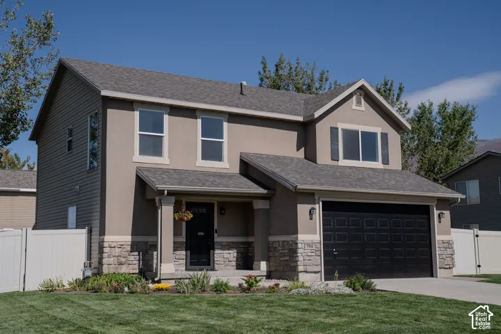 Two-story residence featuring a covered entry, attached garage, and stone facade accents