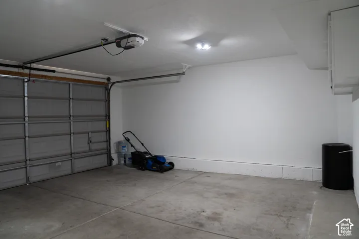 Attached garage with concrete flooring, automatic garage door opener, and overhead lighting