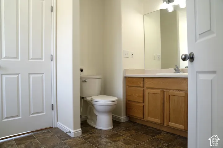 Bathroom featuring a light wood-finish vanity with a light countertop, integrated sink, and wall-mounted mirror