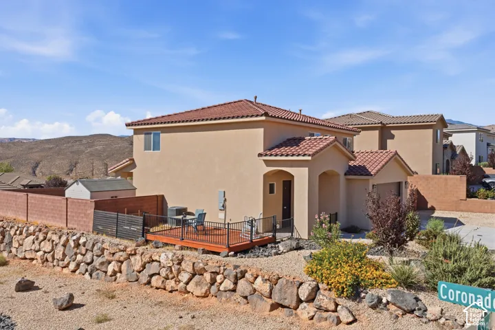 Exterior features a stucco finish, tile roof, and a wood-decked patio with black railings