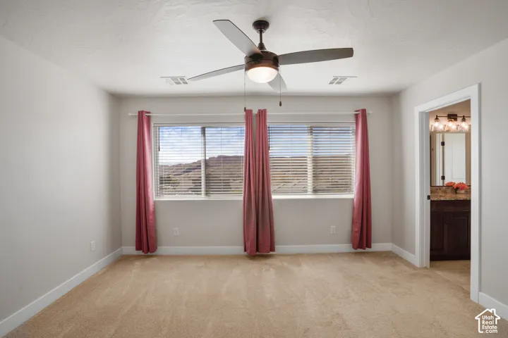 Primary Bedroom. Ceiling fan with integrated lighting, two windows with blinds, and a neutral carpet
