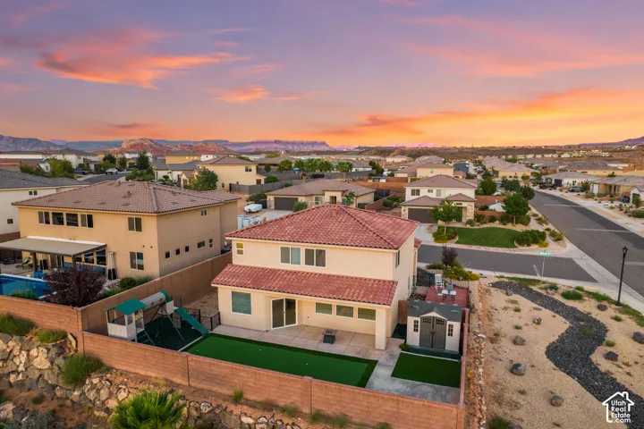 Stucco exterior residence with a red tile roof, featuring a private fenced yard with artificial turf and a patio