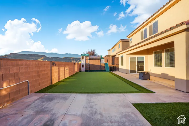 Expansive concrete patio with artificial turf, complete with a block wall perimeter and a covered outdoor area