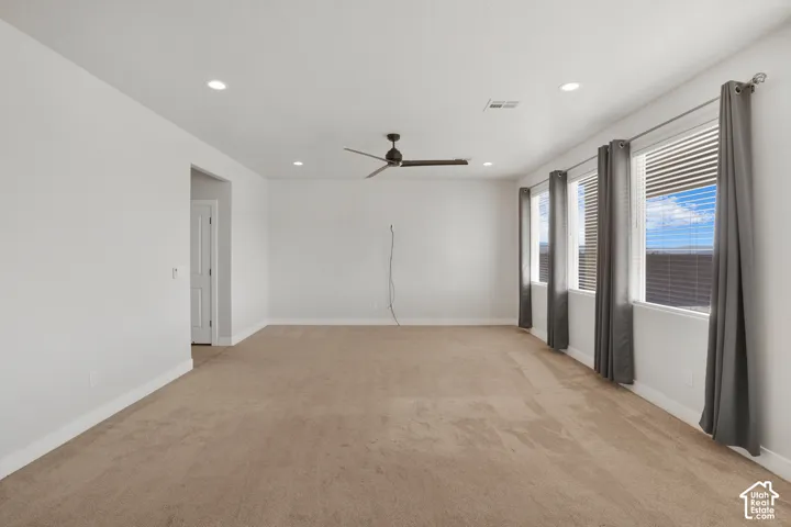 Recessed lighting, ceiling fan, multiple windows, and neutral carpeting