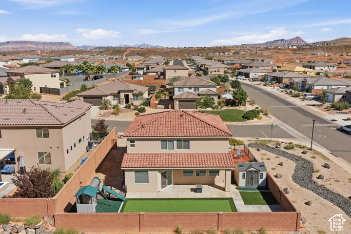Stucco exterior with a tile roof, featuring a private fenced yard with artificial turf and a patio